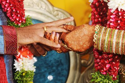 Cropped hands of bride and bridegroom exchanging rings