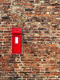 Red mailbox on brick wall