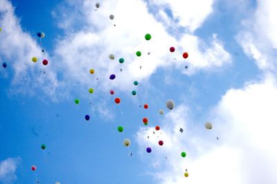 Low angle view of balloons flying against cloudy sky