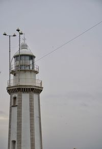 Low angle view of lighthouse by building against sky