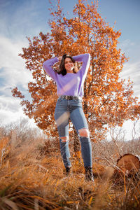 Full length of young woman standing on field during autumn