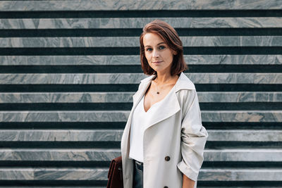 Young woman standing against wall