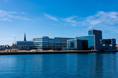 Buildings by river against sky