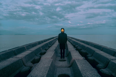 Rear view of man standing on rocks against sea and sky