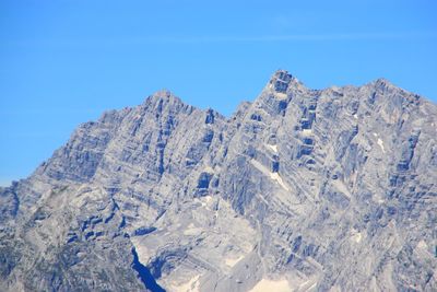 Low angle view of snowcapped mountain against blue sky