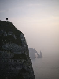 Silhouette person standing on cliff at etretat against sky