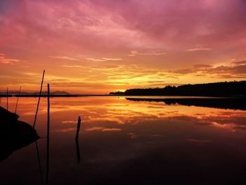 Scenic view of lake against dramatic sky during sunset