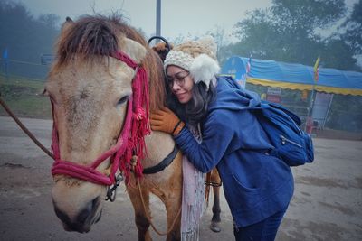 Woman with horse standing on field