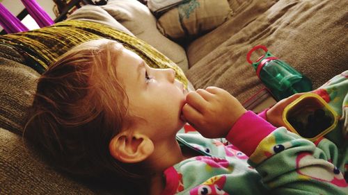 High angle view of cute baby girl relaxing on sofa at home