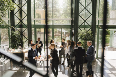 Businessmen and businesswomen discussing while standing around tables at convention center