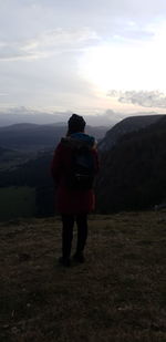 Rear view of man standing on mountain against sky