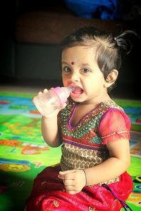 Portrait of cute baby girl drinking water from milk bottle at home