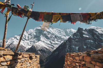 Built structure hanging on snowcapped mountains against sky