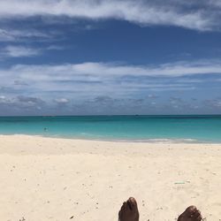 Low section of person on beach against sky