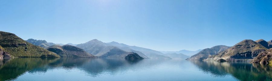 Scenic view of lake and mountains against clear blue sky