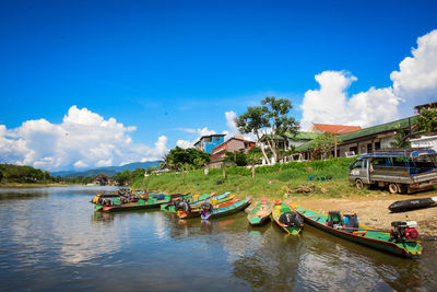 Boats moored in water against sky