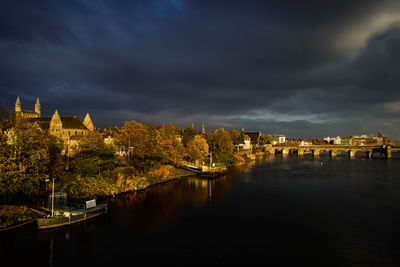 Church by river against cloudy sky