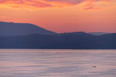 Scenic view of lake and mountains against orange sky
