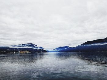 Scenic view of lake by snowcapped mountains against sky