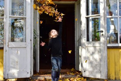 Boy throwing dry leaves against door