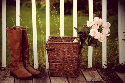 Leather boots by pink roses in wicker basket