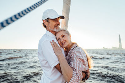 Senior couple embracing while standing on yacht in sea