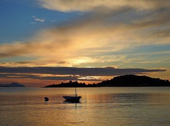 Silhouette boats in sea against sky during sunset