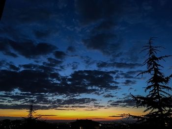 Low angle view of silhouette trees against dramatic sky