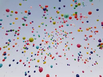 Low angle view of balloons flying against sky