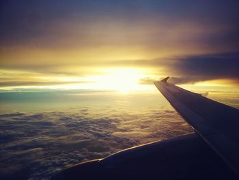 Cropped image of airplane flying over sea at sunset