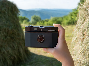 Midsection of person photographing camera on land