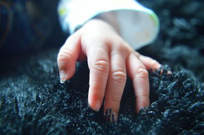 Cropped hand of baby on blanket