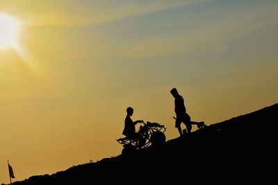 Low angle view of silhouette people against orange sky