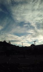 Street by silhouette buildings against sky at sunset