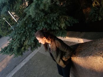 Side view of girl leaning on retaining wall against plants