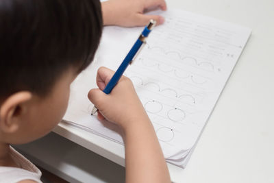 Close-up of boy writing in book at table