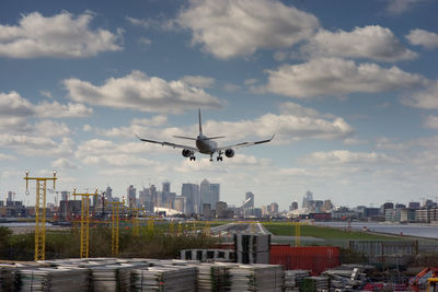 Airplane flying over cityscape against sky