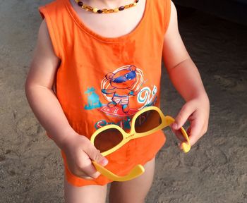 Close-up of boy holding sunglasses at beach