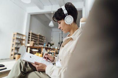 Artist with headphones sketching pot on book at workshop