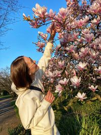 Rear view of woman standing amidst flowering plants against sky