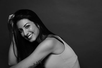 Portrait of young woman against black background