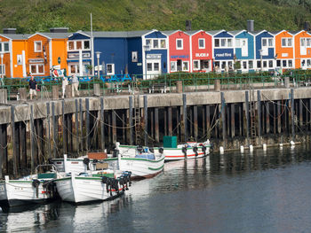 Boats moored in canal by houses in city