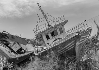 Old boat moored on land against sky