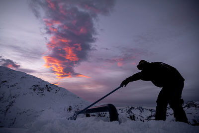 Man standing on snowcapped mountain against sky during winter