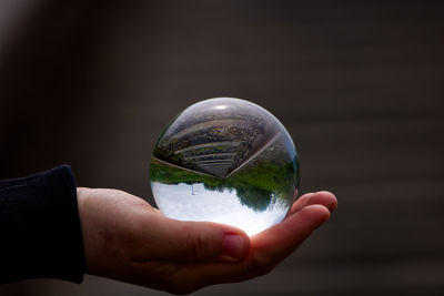 Cropped image of hand holding crystal ball glass