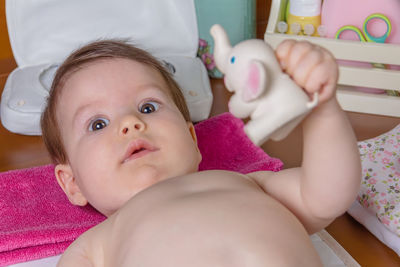 Portrait of baby girl holding toy animal at home