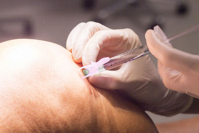 Close-up of doctor injecting patient on knee