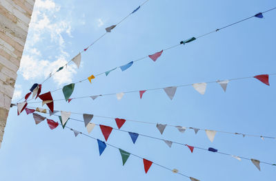 Several strings of multicolored bunting flags against blue sky