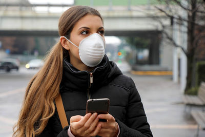 Portrait of young woman using smart phone on street