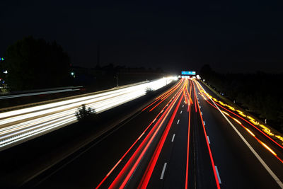 Light trails on road against sky at night